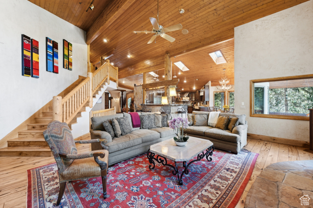 Living room featuring wood ceiling, a high ceiling, wood-type flooring, and ceiling fan with notable chandelier