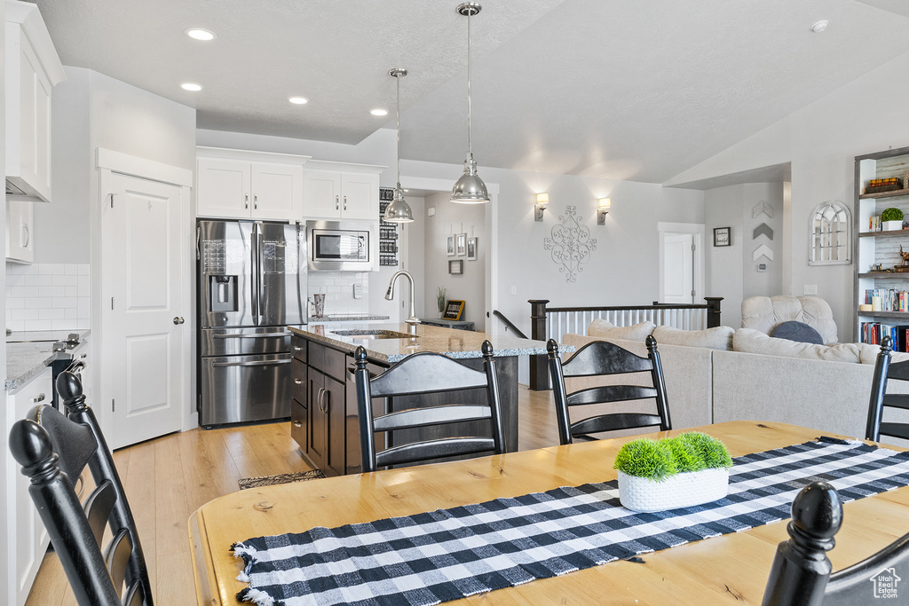 Dining area with vaulted ceiling, light hardwood / wood-style flooring, and sink