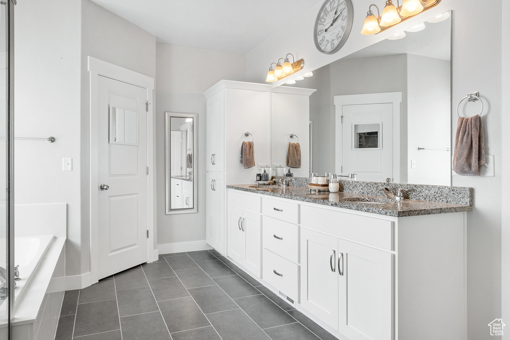 Bathroom featuring tiled bath, tile patterned flooring, and double vanity