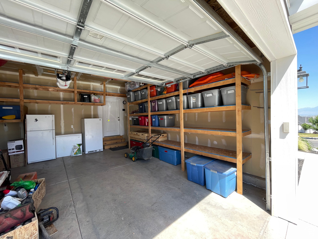 Garage featuring a garage door opener and white refrigerator