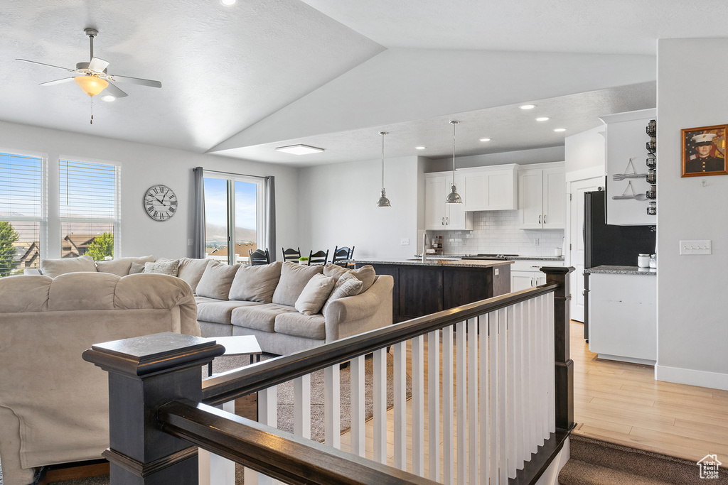 Living room with sink, light wood-type flooring, ceiling fan, and lofted ceiling