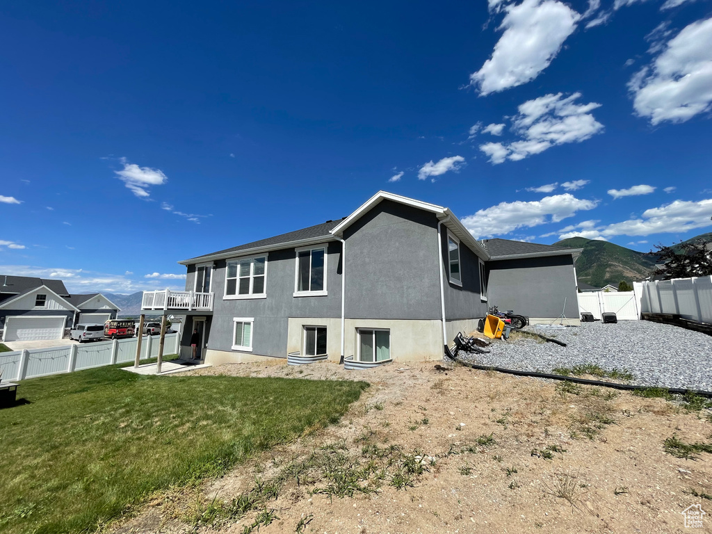 Back of house featuring a patio area, a lawn, and a mountain view