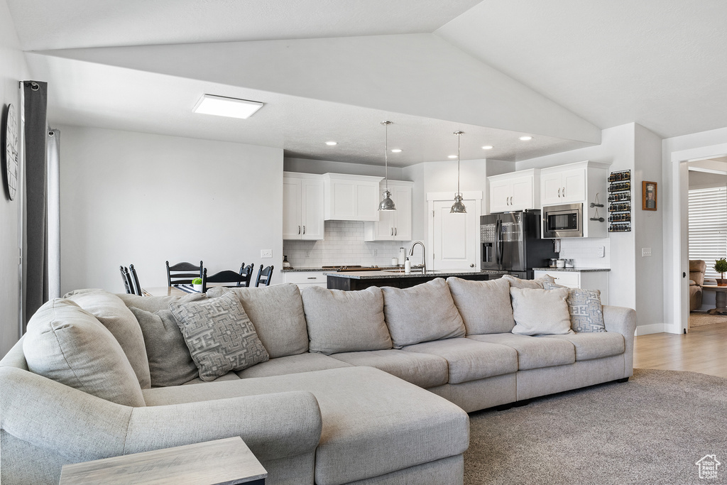 Living room with vaulted ceiling, sink, and light hardwood / wood-style floors