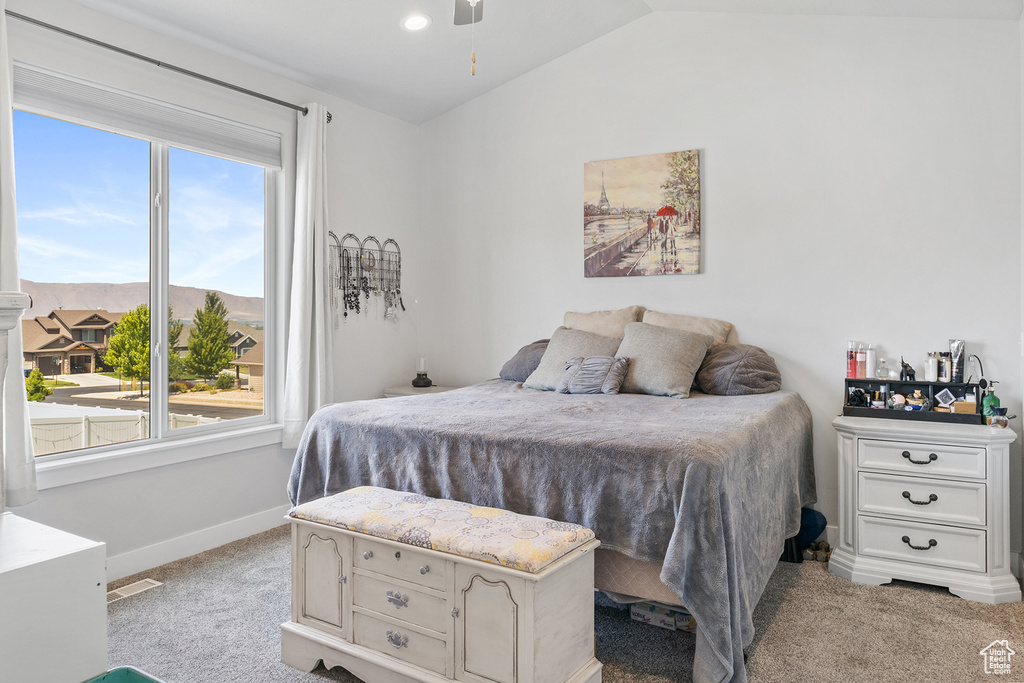 Bedroom with lofted ceiling, light carpet, and multiple windows