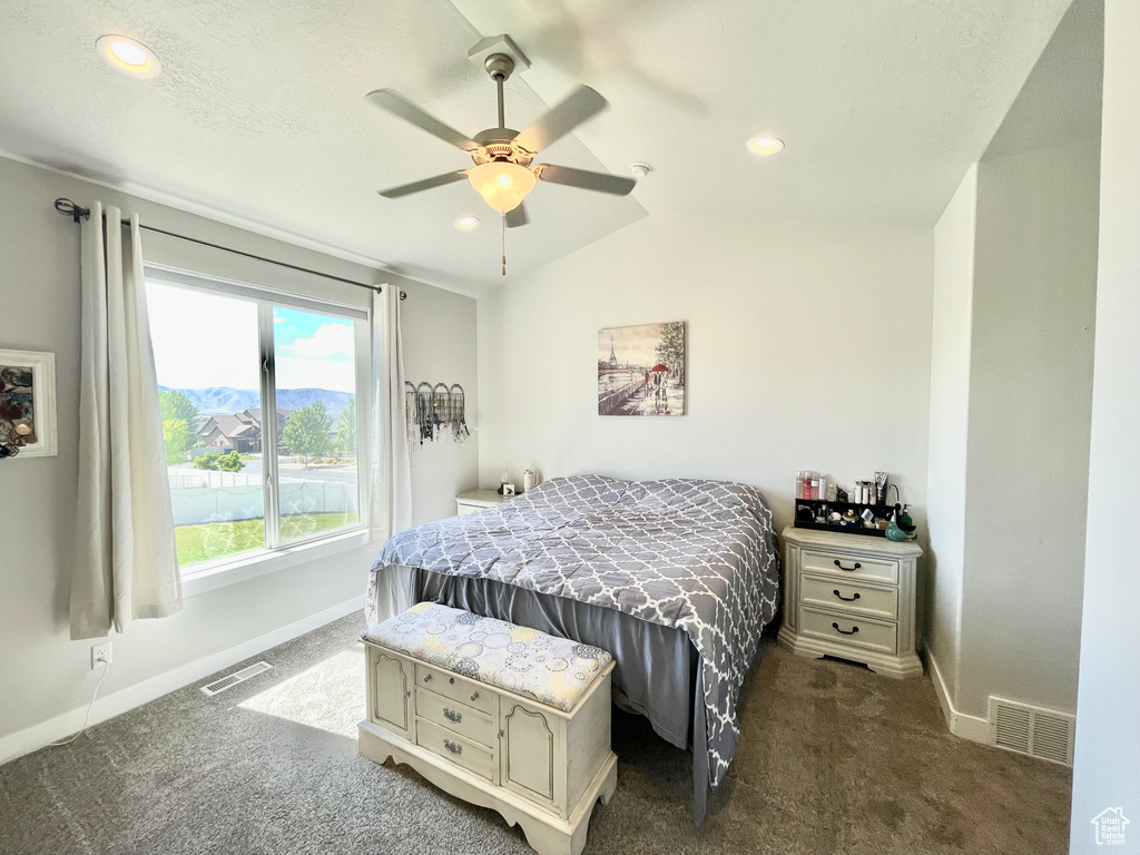 Carpeted bedroom with ceiling fan and lofted ceiling