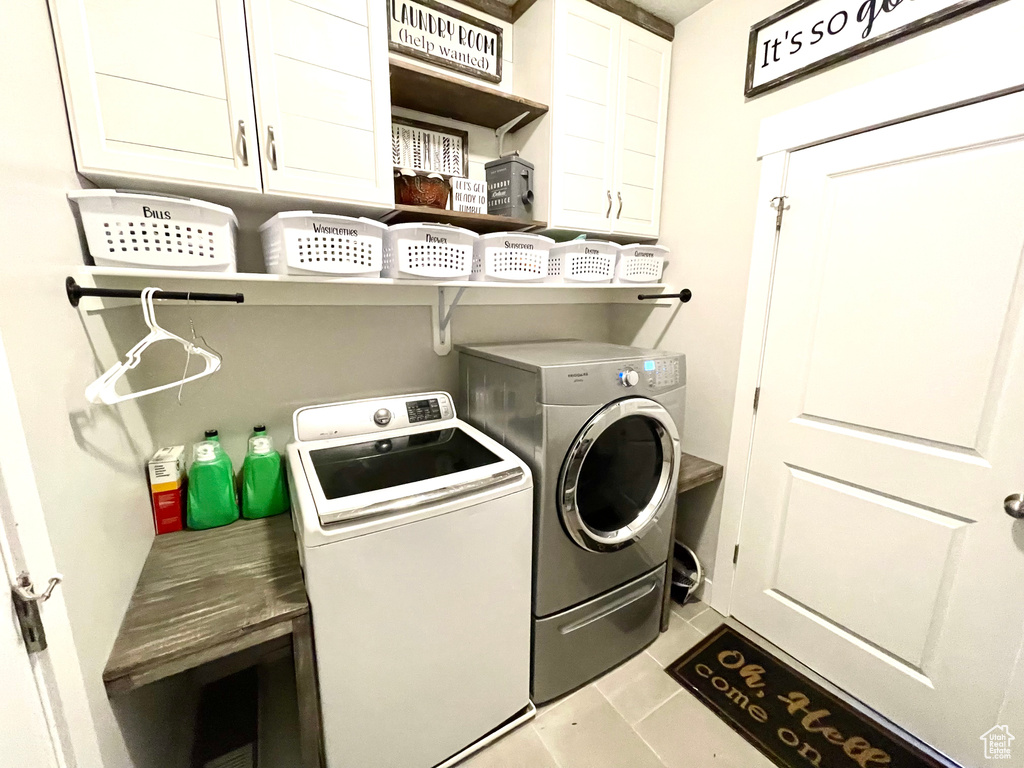 Laundry room featuring light tile patterned flooring, washer and clothes dryer, and cabinets