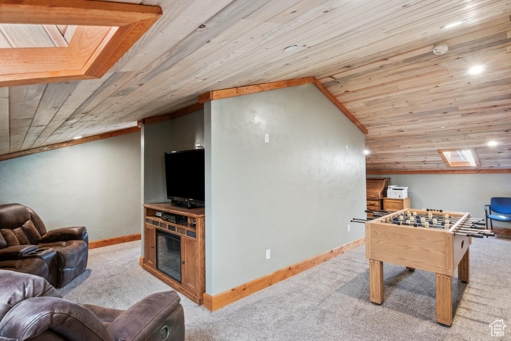 Recreation room featuring wooden ceiling, light carpet, and vaulted ceiling with skylight