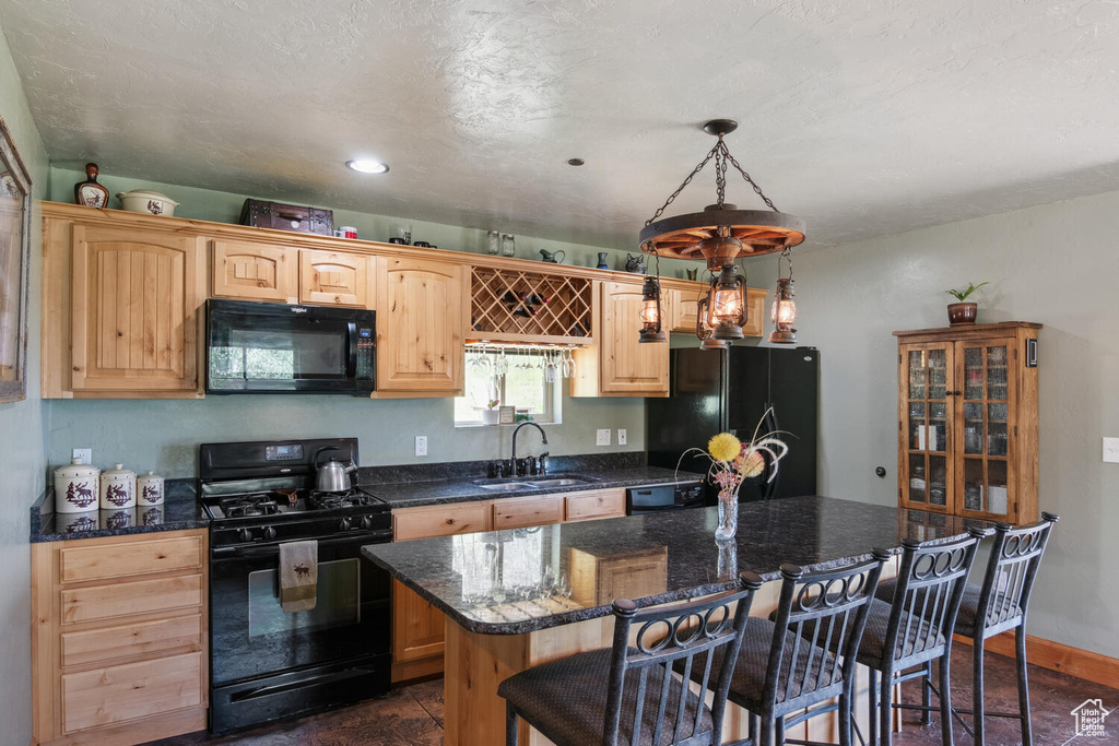 Kitchen with a kitchen breakfast bar, black appliances, hanging light fixtures, a center island, and sink