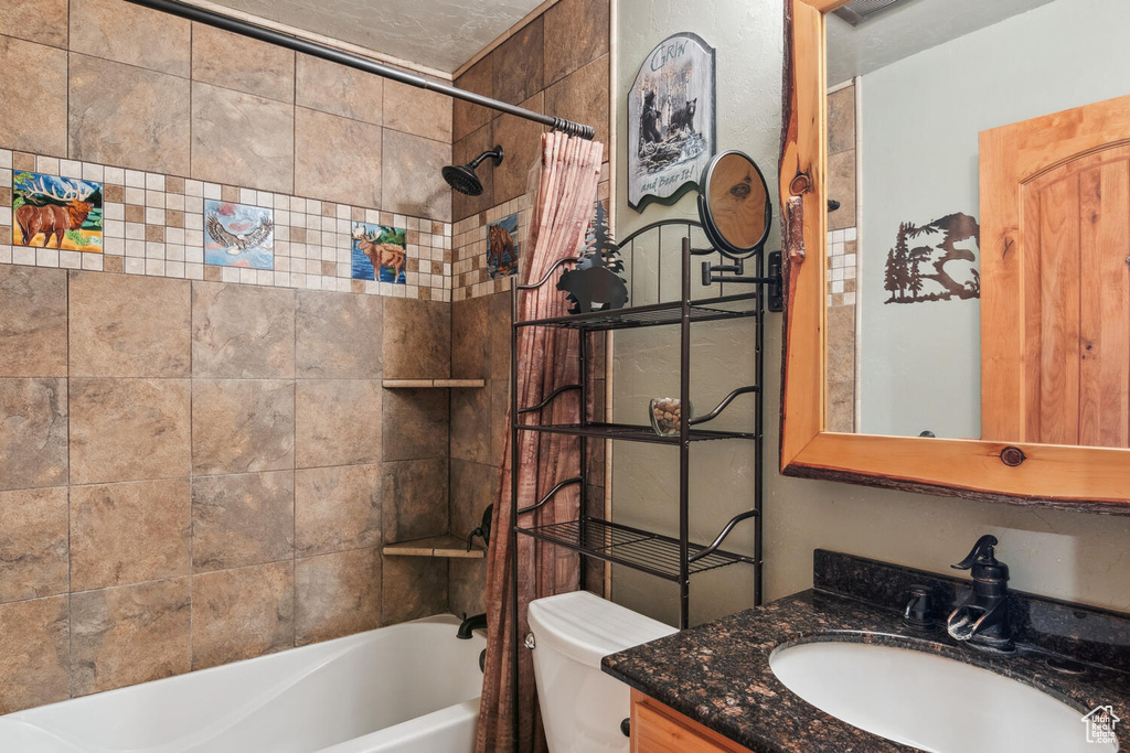 Full bathroom with toilet, vanity, and shower / bath combo