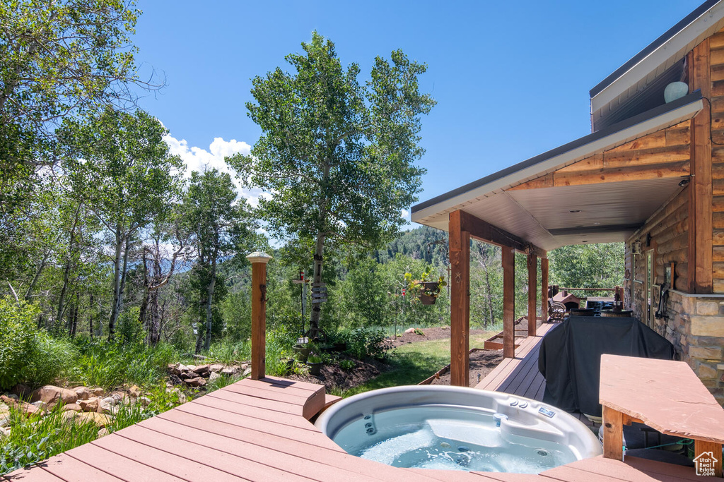 Wooden terrace with an outdoor hot tub and area for grilling