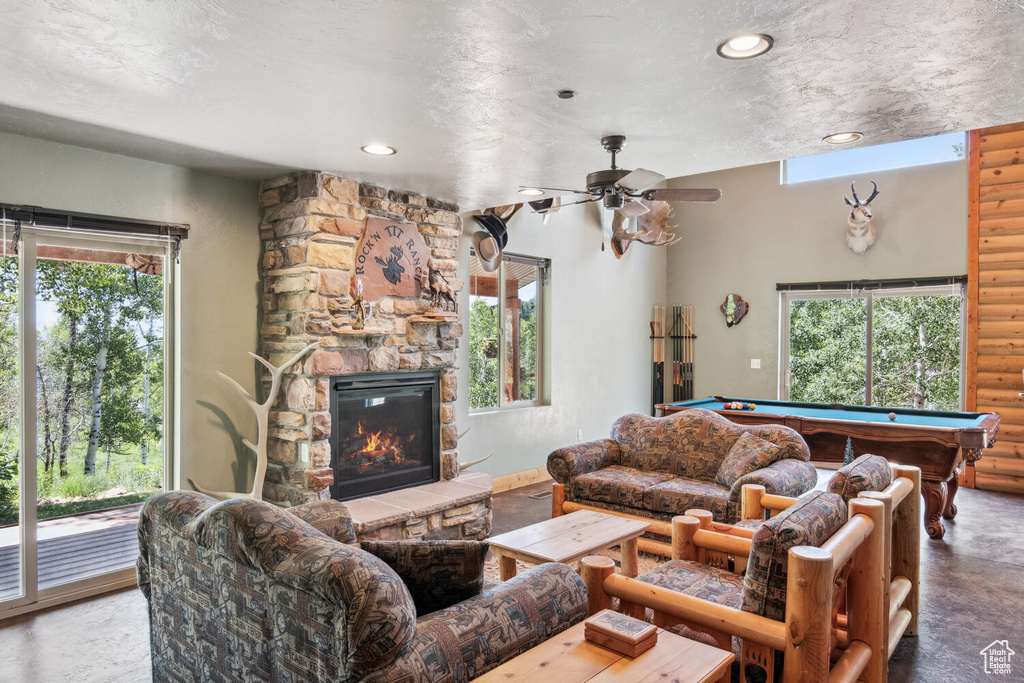 Living room with a wealth of natural light, rustic walls, a fireplace, and pool table