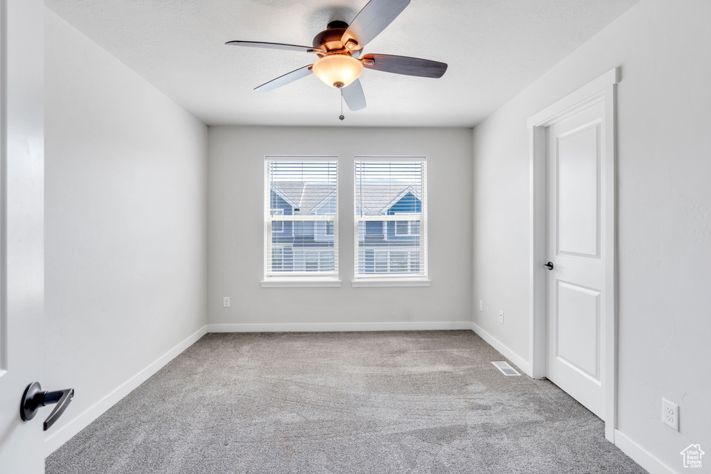 Carpeted empty room featuring ceiling fan