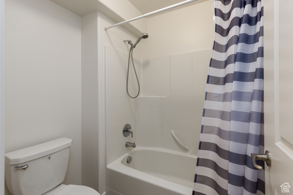 Bathroom featuring toilet and shower / tub combo with curtain