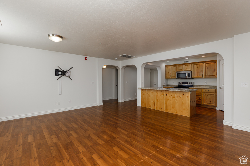 Kitchen featuring appliances with stainless steel finishes, dark hardwood / wood-style flooring, and a center island