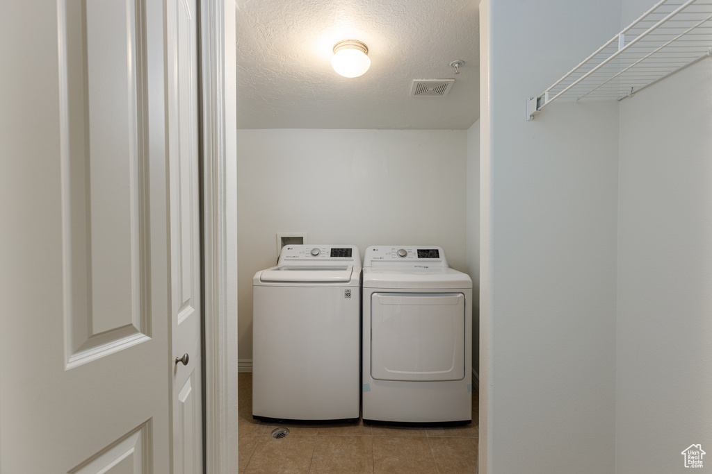 Laundry room featuring separate washer and dryer and light tile floors