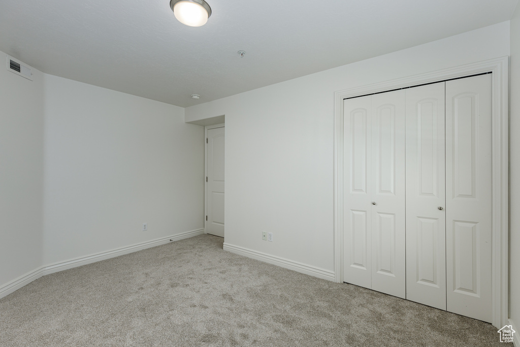 Unfurnished bedroom featuring light colored carpet and a closet