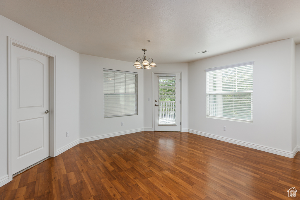 Spare room with a notable chandelier and wood-type flooring