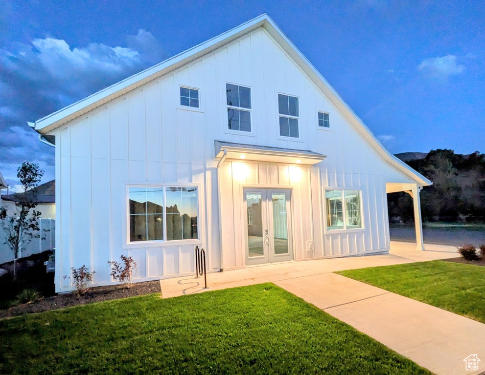 Back of property with a lawn, a patio, and french doors