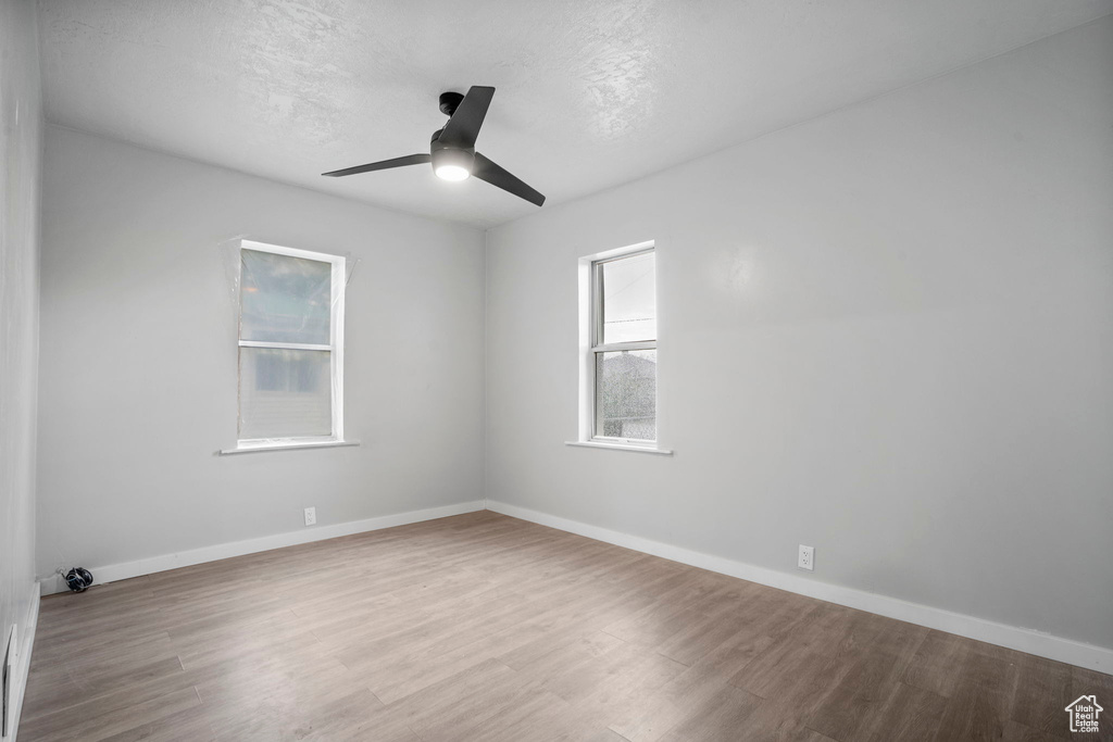 Empty room with ceiling fan and hardwood / wood-style flooring