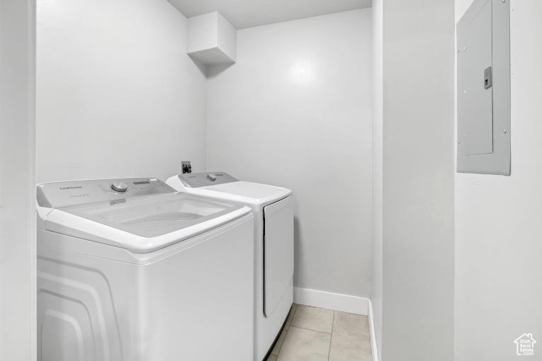 Washroom featuring washing machine and clothes dryer and light tile floors