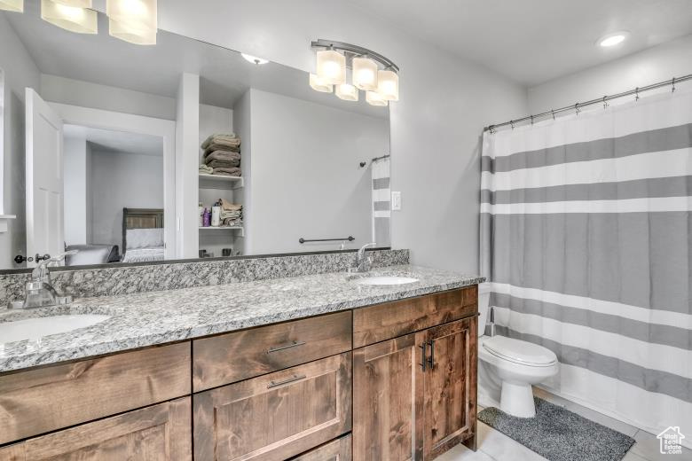 Bathroom featuring double sink, toilet, tile floors, and large vanity