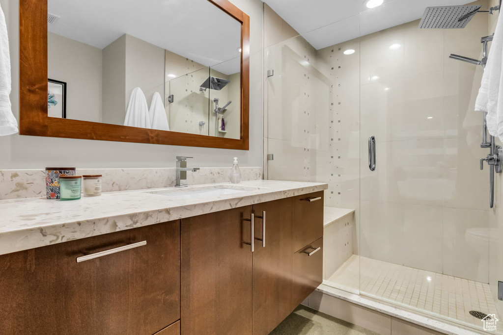 Bathroom featuring a shower with door and large vanity