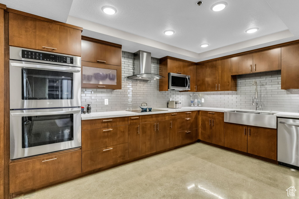 Kitchen with backsplash, wall chimney range hood, sink, and stainless steel appliances