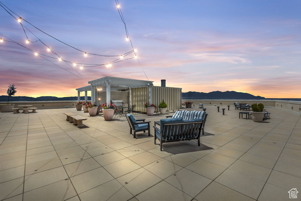 Patio terrace at dusk with a pergola, a mountain view, and an outdoor hangout area