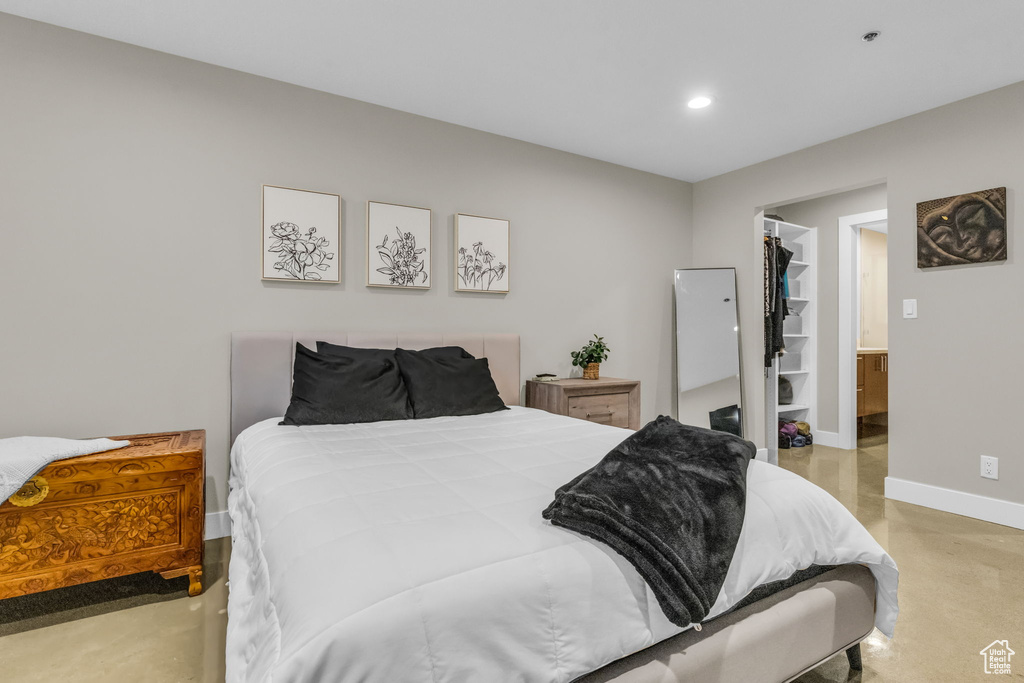 Bedroom featuring concrete floors, a walk in closet, and a closet