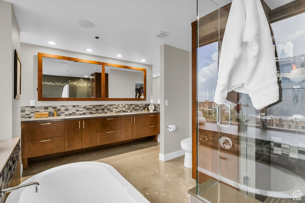 Full bathroom featuring a wealth of natural light, backsplash, vanity, and toilet