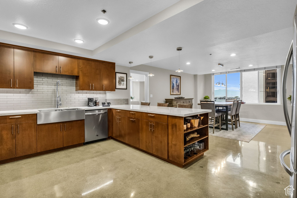 Kitchen featuring appliances with stainless steel finishes, kitchen peninsula, pendant lighting, sink, and tasteful backsplash