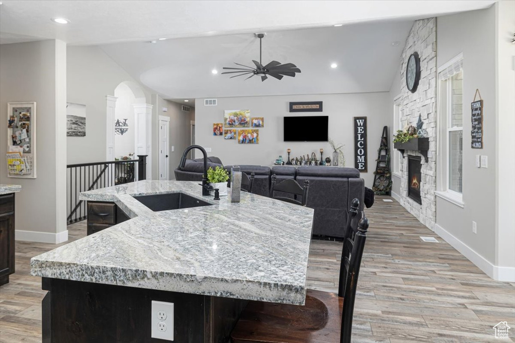 Kitchen with ceiling fan, light hardwood / wood-style flooring, vaulted ceiling, a fireplace, and sink