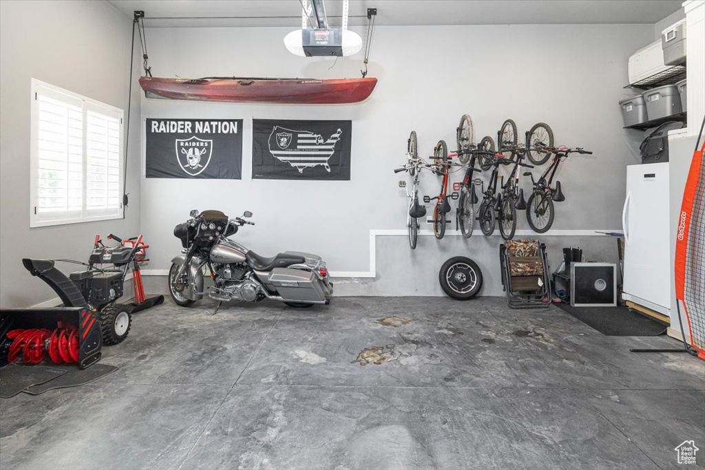 Garage featuring white fridge and a garage door opener