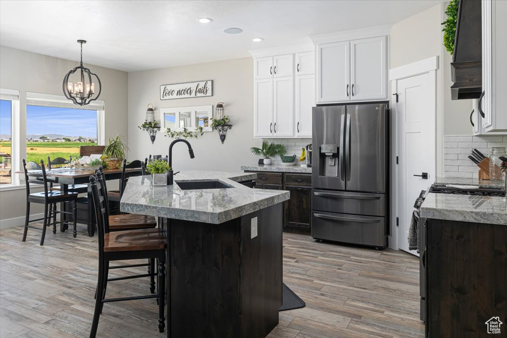 Kitchen with stainless steel refrigerator with ice dispenser, wood-type flooring, sink, and backsplash