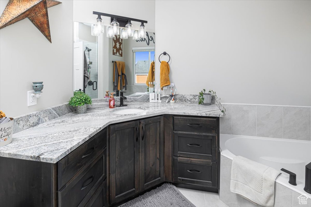 Bathroom featuring tiled bath, vanity, and tile floors