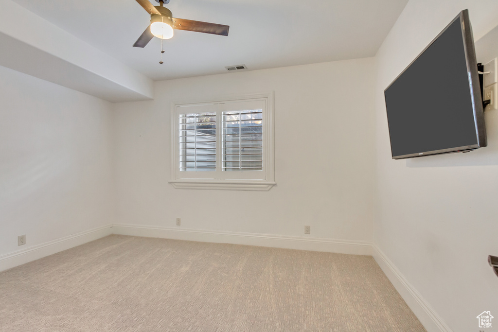 Unfurnished room with light colored carpet and ceiling fan