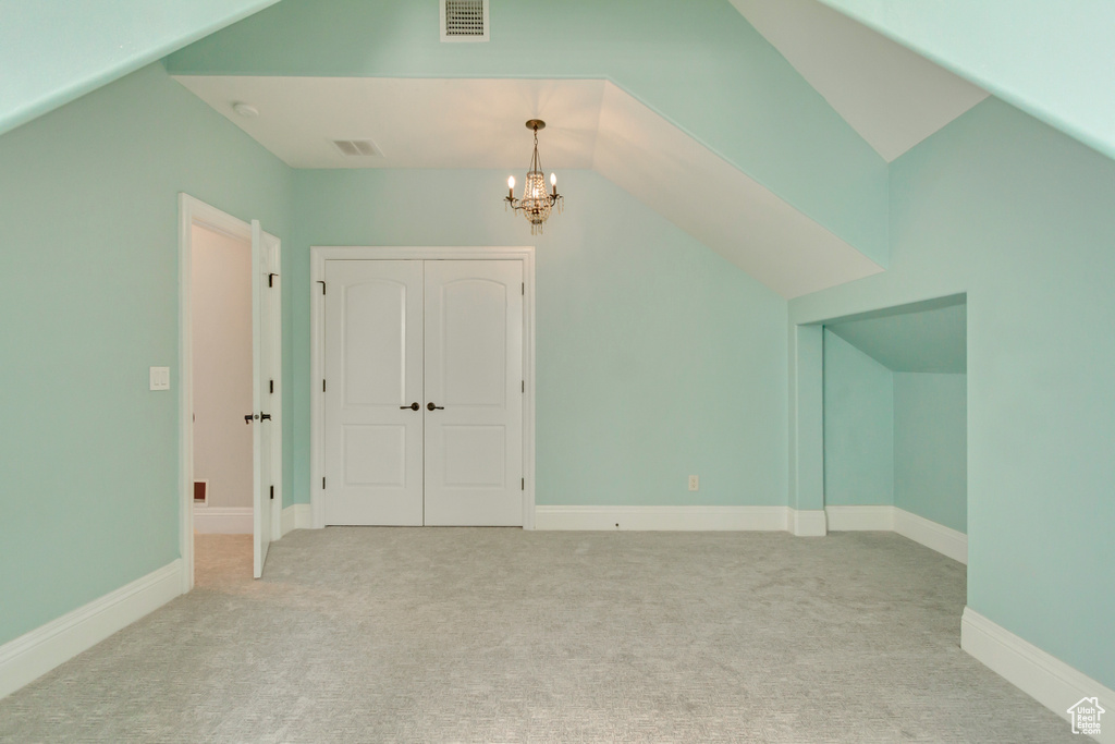 Additional living space featuring lofted ceiling, a chandelier, and light carpet