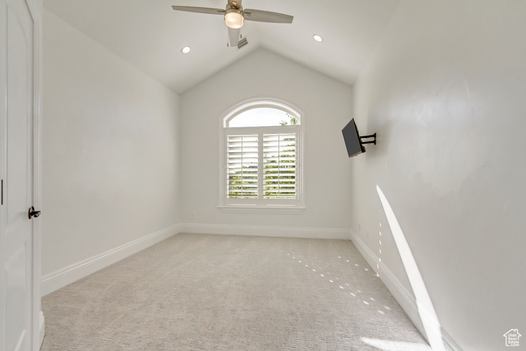 Empty room with lofted ceiling, light colored carpet, and ceiling fan