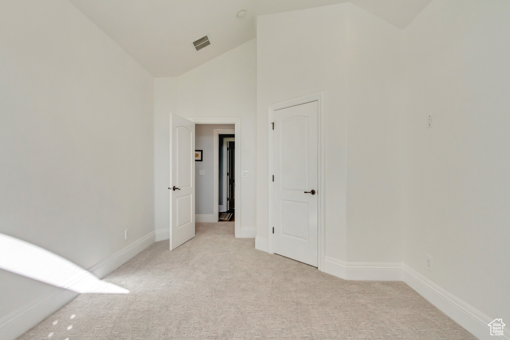 Carpeted empty room with high vaulted ceiling