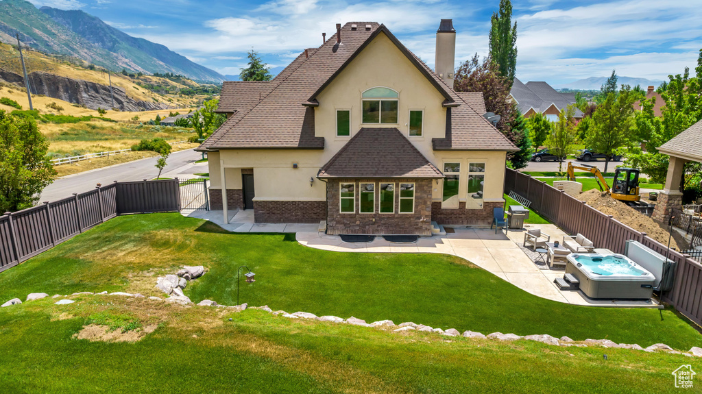 Back of house with a patio, a mountain view, and a lawn