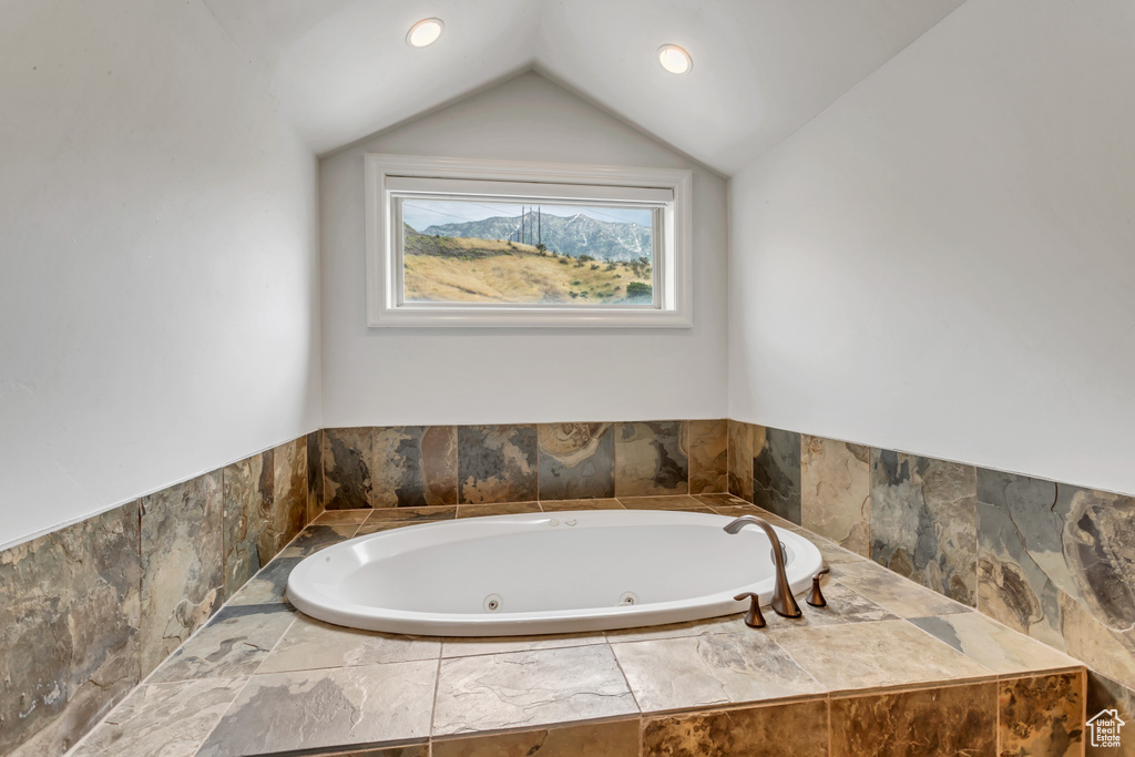 Bathroom with vaulted ceiling and a relaxing tiled tub