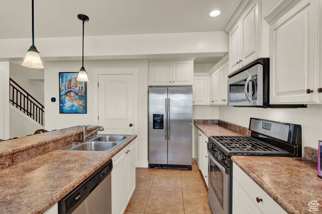 Kitchen featuring white cabinets, decorative light fixtures, light tile flooring, stainless steel appliances, and sink