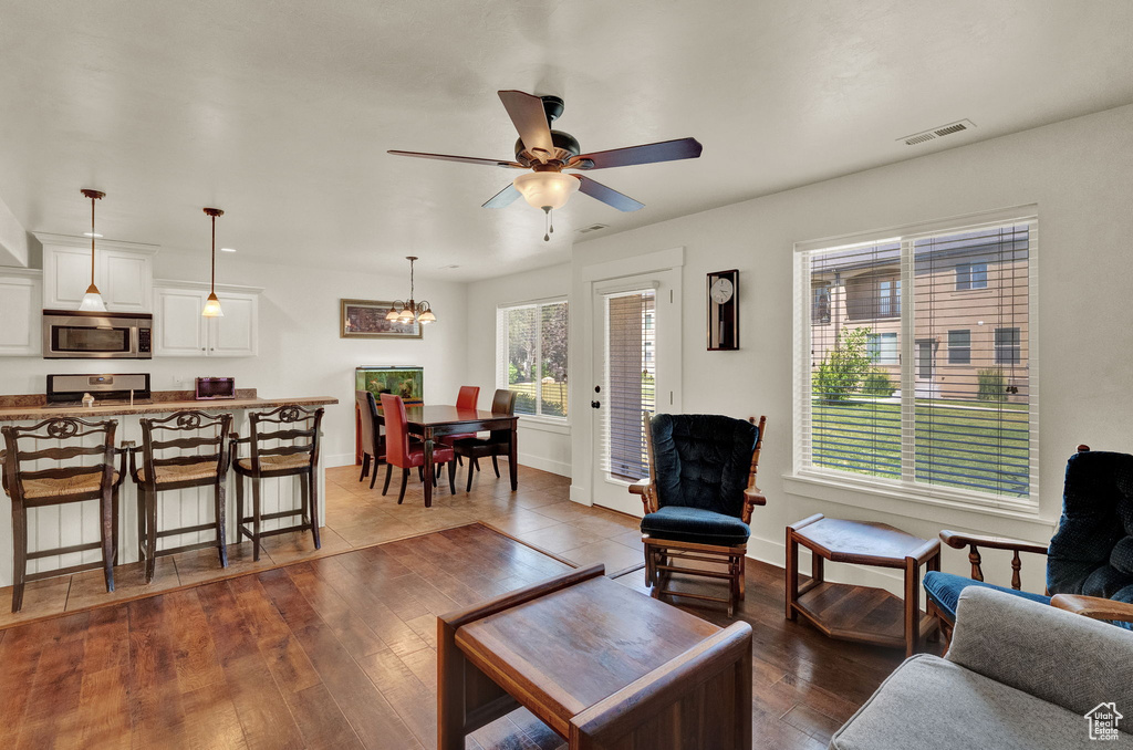 Tiled living room featuring ceiling fan with notable chandelier