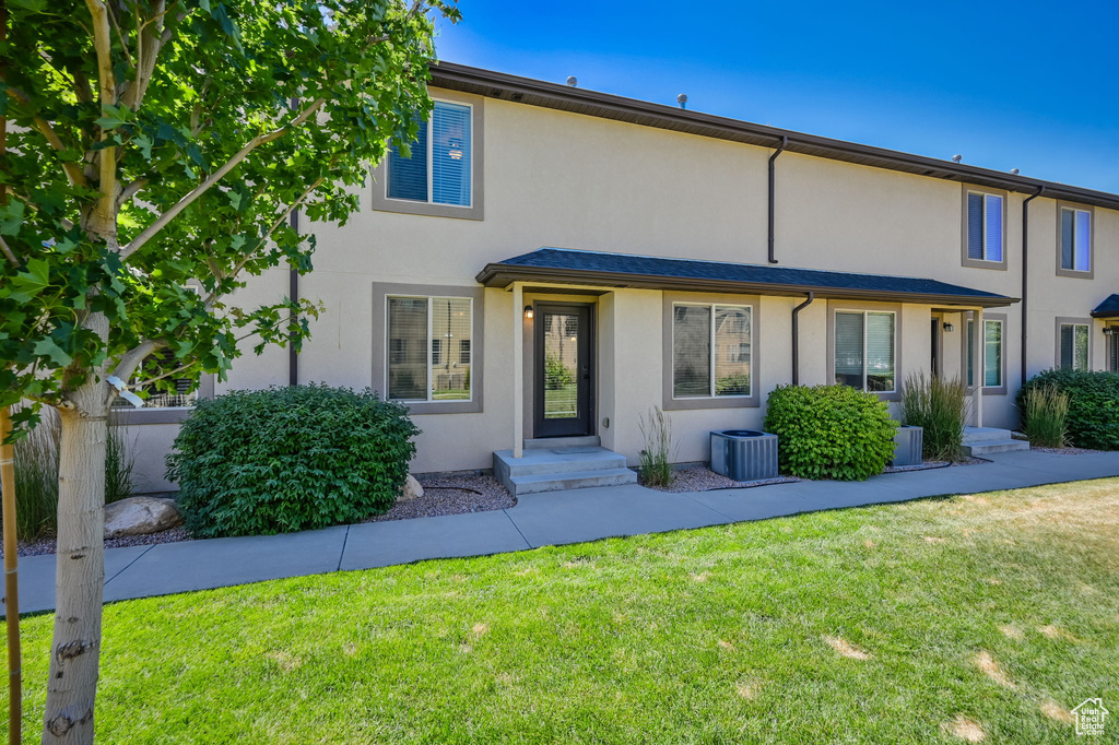 View of front of home with central AC and a front lawn