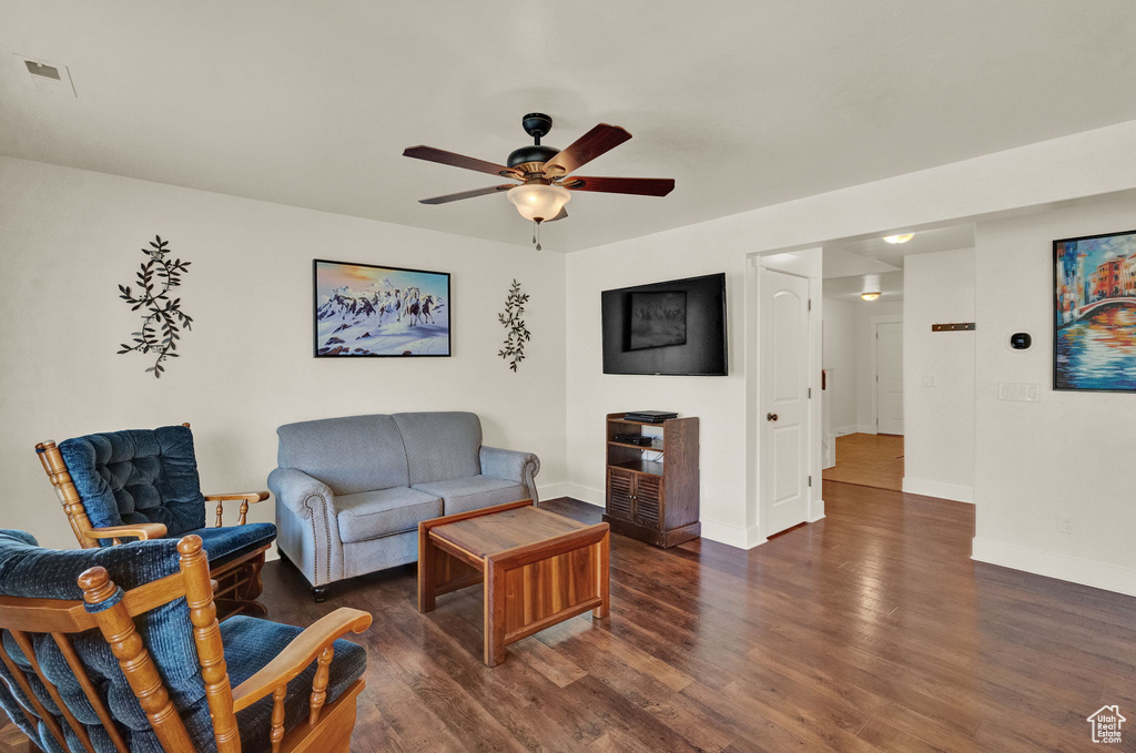 Living room with ceiling fan and dark wood-type flooring