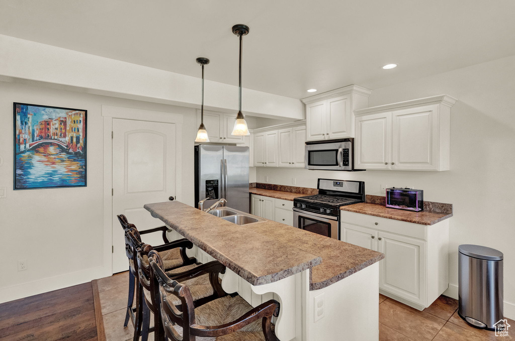 Kitchen featuring an island with sink, sink, white cabinetry, and appliances with stainless steel finishes