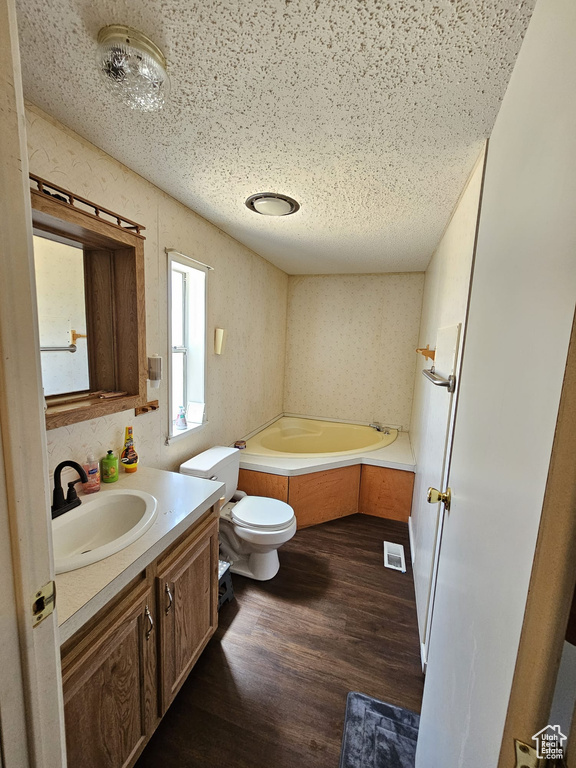 Bathroom with toilet, hardwood / wood-style flooring, a bathtub, vanity, and a textured ceiling