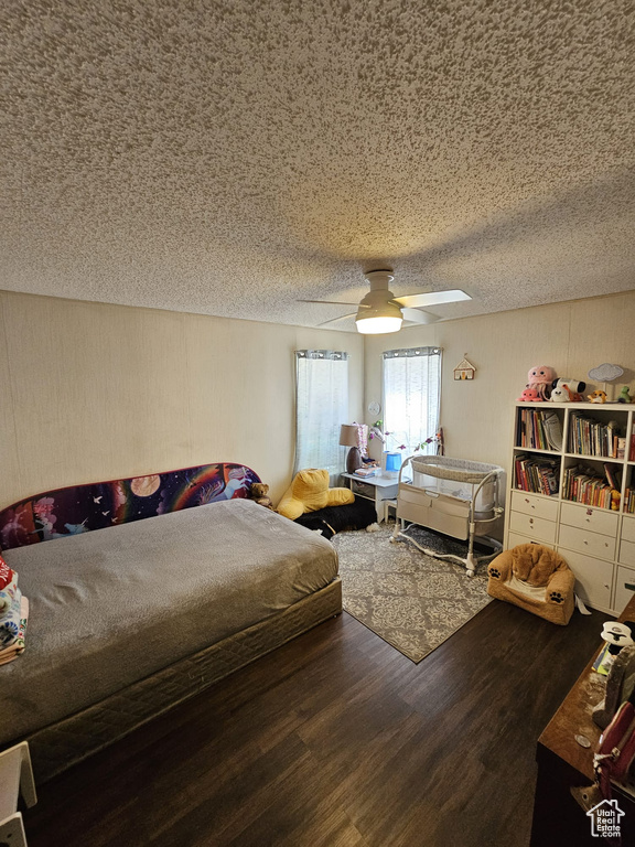 Bedroom featuring dark hardwood / wood-style floors, ceiling fan, and a textured ceiling