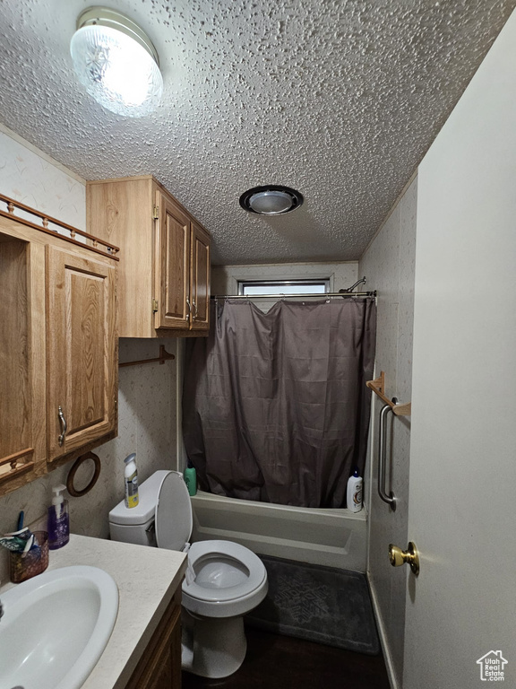 Full bathroom with shower / bathtub combination with curtain, a textured ceiling, toilet, and vanity