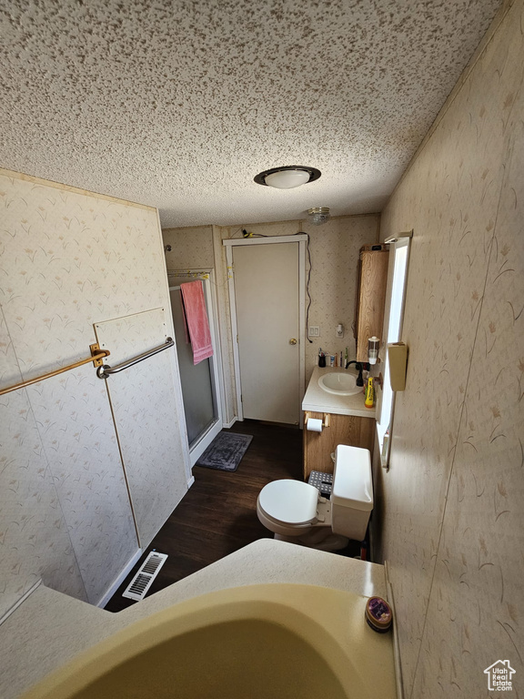 Bathroom featuring a textured ceiling, wood-type flooring, vanity, and a tub